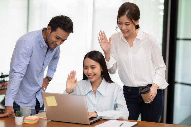 Group of Young business woman meeting with Customer or business team via video conference call at Office,Hand up Greetings with group in online video call